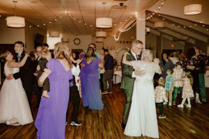 Father and bride dance amongst a packed wedding reception dance floor with friends and family at the Gold Star Venue at the VFW in Rochester, Minnesota.